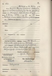 Zdjęcie przedstawia archiwalny, pionowy dokument papierowy o jasnym, kremowym odcieniu, wypełniony odręcznym pismem w języku niemieckim. Formularz zawiera drukowane linie i sekcje, z których środkowa część została przekreślona dwiema długimi, ukośnymi liniami tworzącymi literę X.